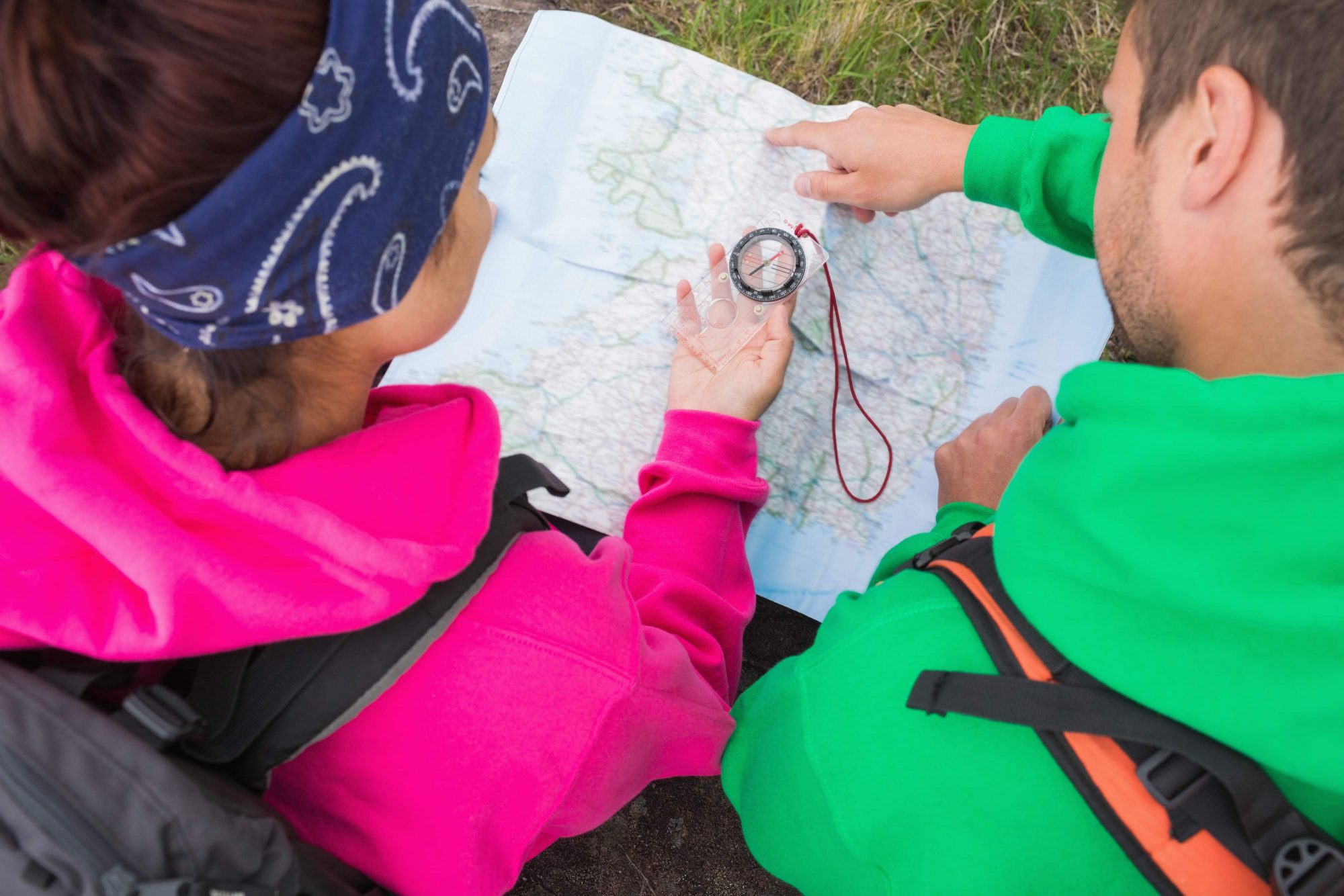 Två personer tittar på en karta med en kompass i handen.