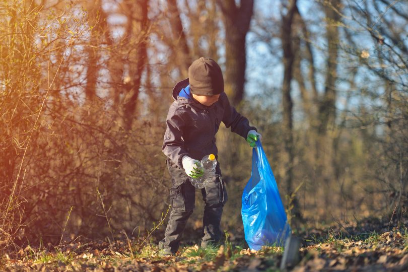 Barn som plockar skräp i naturen