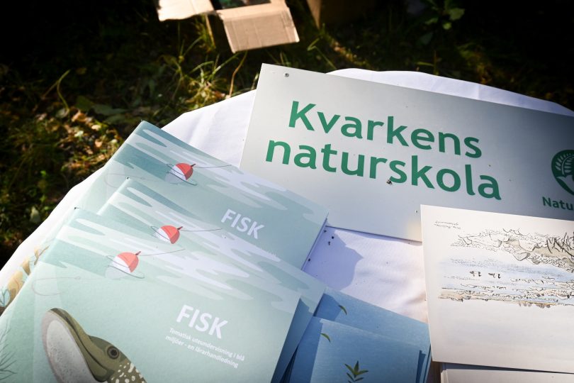 Affischer, bilder och material för kvarkens naturskola ligger utomhus i skogen.