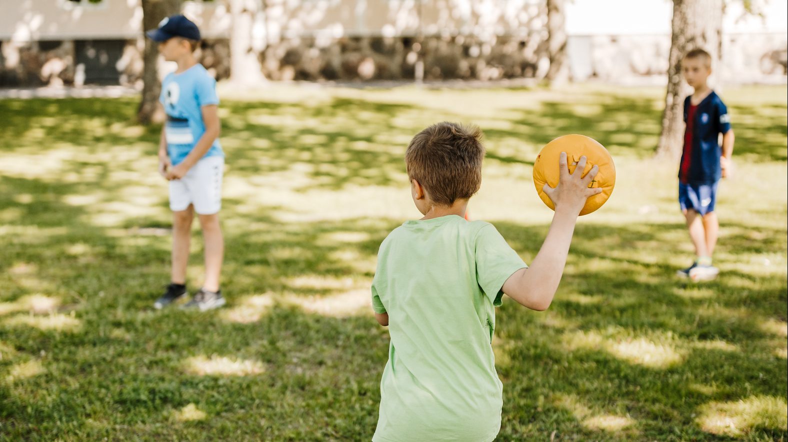 Ett barn håller en boll i handen och är redo att kasta den iväg.