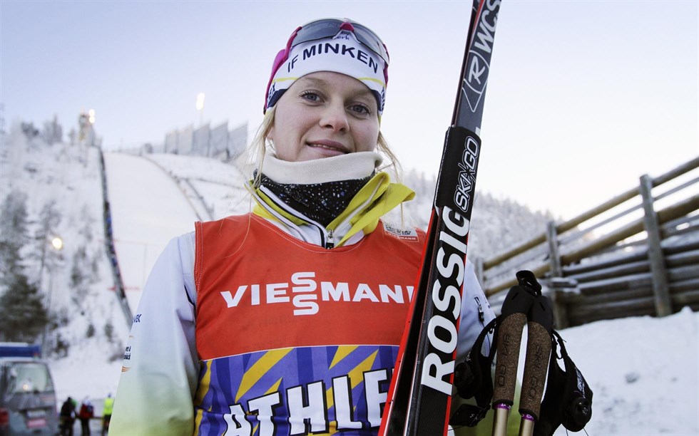 En bild på elitskidåkaren Andrea Julin när hon håller i sina skidor och stavar.