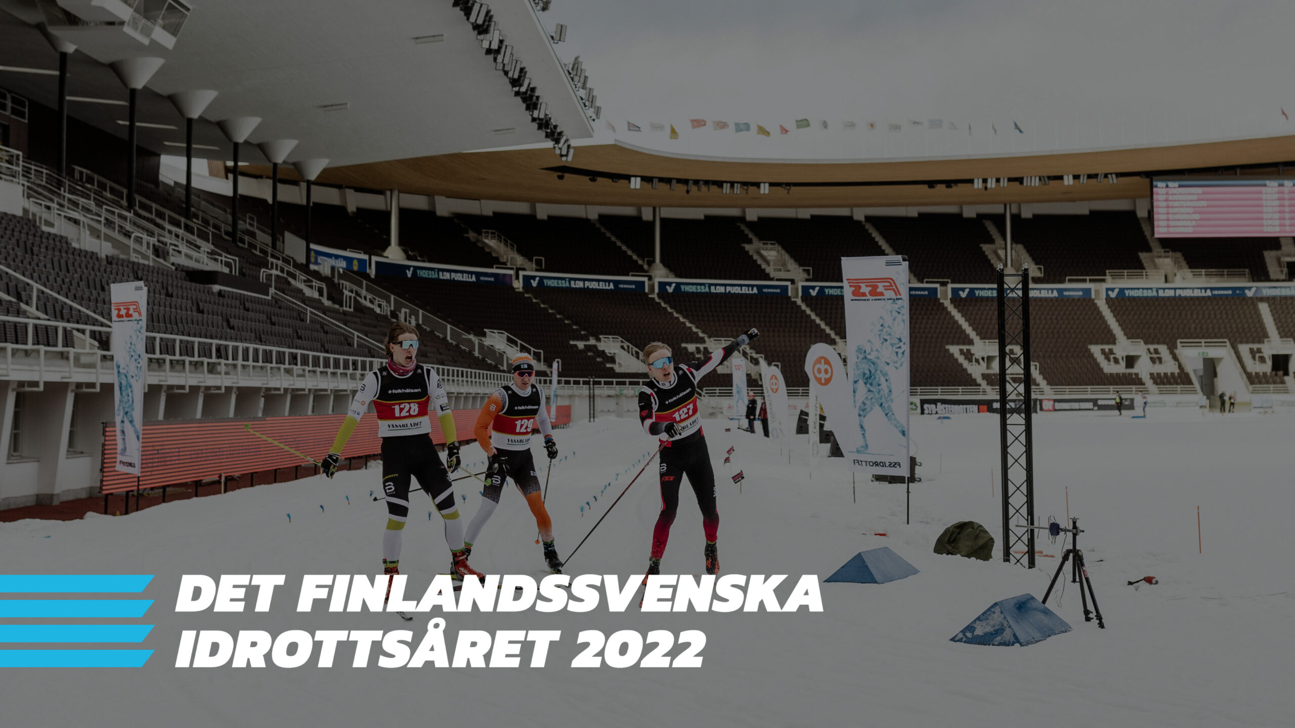 Tre skidåkare när slutet på ett lopp. Längst ner på bilden ser man i vitt " det finlandssvenska idrottsåret 2022" och i blått FSIs logo.